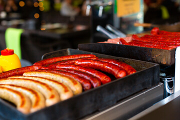 Juicy appetizing grilled sausages in a metal tray. Street food counter
