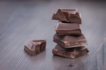 Pieces of dark chocolate on brown wooden background. Copy space.