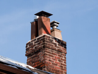 a brick residential rooftop fireplace chimney with a rain cap