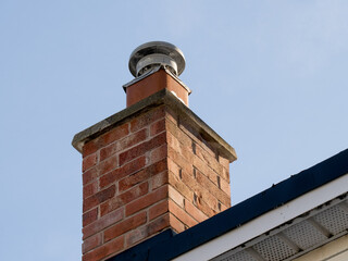 a brick residential gas furnace chimney with a flue liner and rain cap