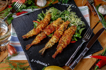 Deep-fried langoustines in batter lie on a plate in a restaurant.