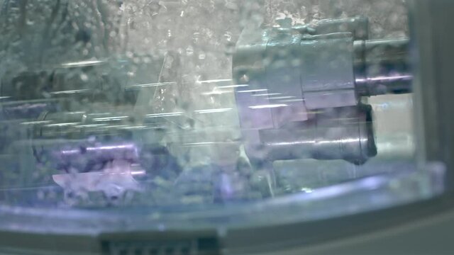 Dental milling machine (CAD/CAM) grinds the dental prosthesis. Creation of a ceramic denture. Grinding a tooth shape with a jet of water according to the 3D model.