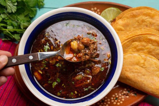 Mexican birria consome soup and tacos on turquoise background