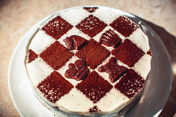 Sponge cake with butter cream. Cake in the form of a chessboard. A gift for the day of a chess player. Cake with chocolate cakes and white pudding. Appetizing dessert.