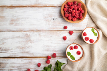 Yogurt with raspberry in clay cups on white wooden background. top view, copy space.