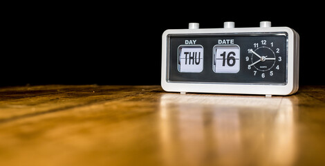 Thursday 16th day of the month, Thursday sixteenth - vintage alarm clock with date on a wooden table - copy space