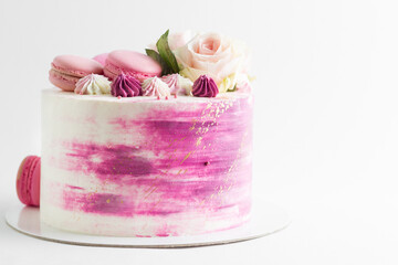 Wedding pink cake with flowers rose and macaroons on top on the white background with copy space at the right.