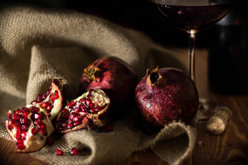 Ripe pomegranate fruit and a glass of wine on a burlap fabric