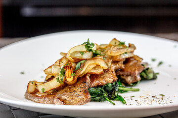 Roast beef liver with spinach and onions on a plate