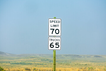 Seventy mph speed limit, Trucks 65 sign on wooden post. Speed zone traffic sign against desert...