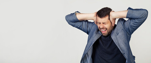 Young businessman man with a beard in a jacket. Hands on head, suffering from headache in despair and under stress due to pain and migraine. Portrait of a man on a gray background