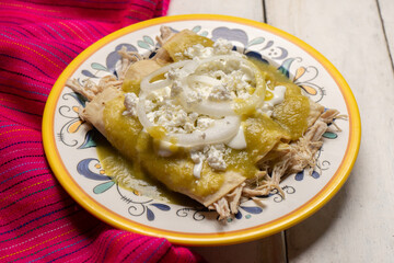Mexican green enchiladas with chicken and cheese on white background