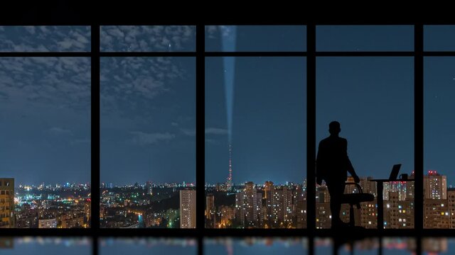 The businessman works in the office on the night urban background. time lapse