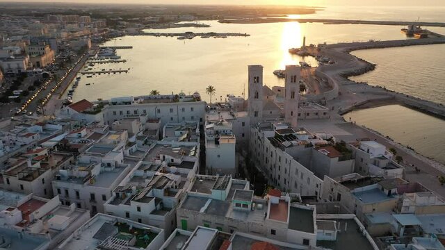 Beautiful panoramic aerial 4K video from flying drone on Molfetta waterfront with the Old Cathedral San Corrado (Duomo Vecchio),port with ships and yachtsand the Molfetta city sunset. Apulia ,Italy