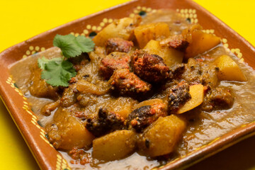 Mexican longaniza with green sauce and potatoes on yellow background