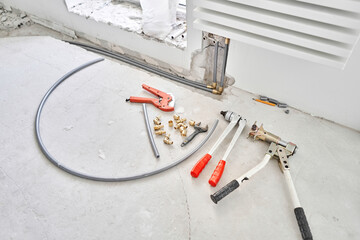 Tools for Work As A Plumber. Connection heating pipes to white Radiator in a new apartment under construction. water heating radiator on the white wall indoors