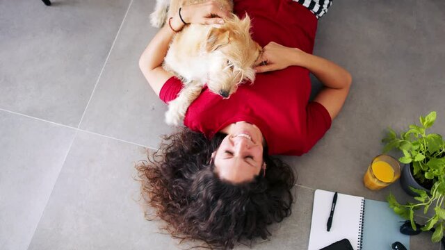 Top view of woman with pet dog lying indoors at home, relaxing.
