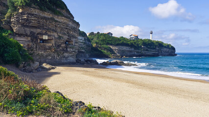 Biarritz lighthouse from the Chambre d'Amour beach with the cave of love chamber in foreground