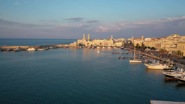 Beautiful panoramic aerial 4K video from flying drone on Molfetta waterfront with the Old Cathedral San Corrado (Duomo Vecchio),port with ships and yachtsand the Molfetta city sunset. Apulia ,Italy