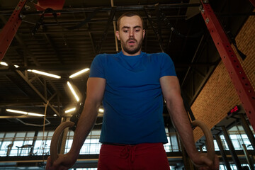 Young Male Athlete With Gymnastic Rings In The Gym. Fitness dip ring man workout at gym dipping...