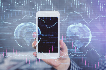 Double exposure of man's hands holding and using a digital device and forex graph drawing. Financial market concept.