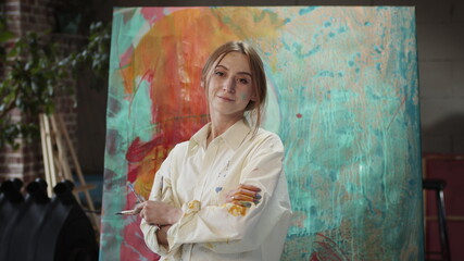 Young Girl Artist Standing Near Painting With Brushes In Her Hands.