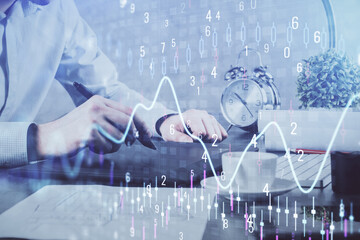 Double exposure of man's hands holding and using a phone and financial graph drawing. Analysis concept.