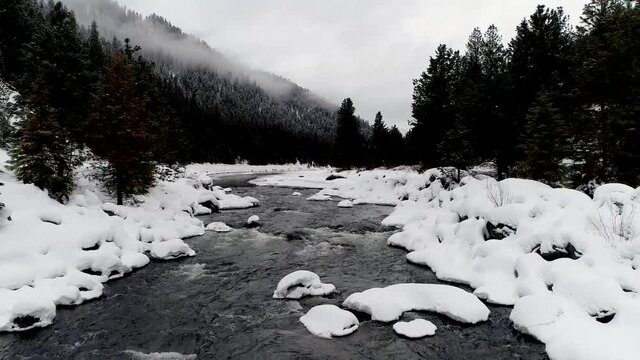 Flying low along the Payette River with snow and then a rising high up reveal drone 4k