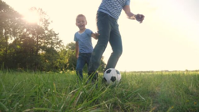 father and son playing football soccer in the park on the grass. happy family dream kid concept. dad and boy play ball outdoor sports in the park healthy. parent lifestyle plays with son into ball
