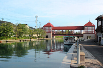 Obraz premium 晴れた日の木造のレトロな赤い橋と穏やかな川