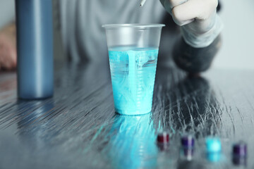 Tattoo artist cleaning machine needle at table, closeup