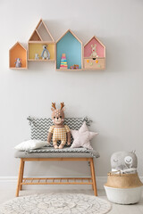 House shaped shelves and bench with toys in children's room. Interior design