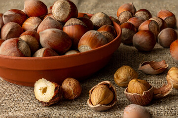 Whole nuts in the shell are on the plate and on the table. Close-up.
