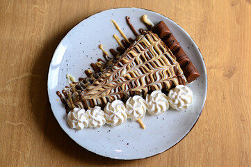 a beautifully decorated caloric pancake full of chocolate.
pancake on a red plate with lots of whipped cream.