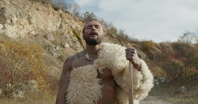A wild nomadic man smells food while hunting with wildlife bows himself.