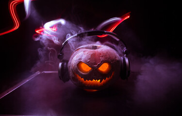 Halloween pumpkin on a dj table with headphones on dark background with copy space. Happy Halloween...