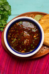Mexican birria consome soup and tacos on turquoise background