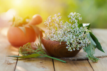 Fresh valerian flowers in wooden plate on table. mortar with prepared potion of valerian root. use...
