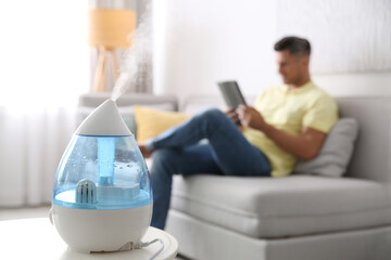 Modern air humidifier and blurred man on background
