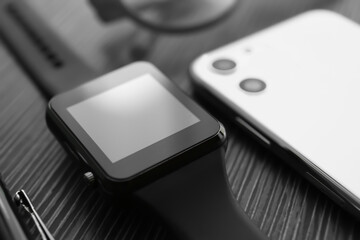 Stylish smart watch and phone on black table, closeup