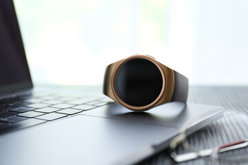 Obraz na płótnie Canvas Stylish smart watch and laptop on table, closeup