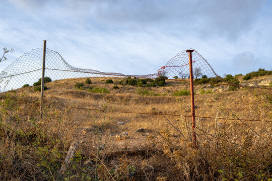 Metal fence in front of the dry field in late summer. Landscape of Castilla la Mancha, Spain