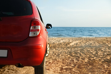 Modern red car on sandy beach, space for text. Summer trip