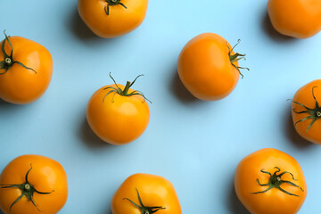 Yellow tomatoes on light blue background, flat lay