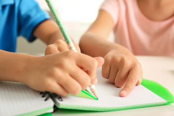 Little boy and girl doing homework at table indoors, closeup