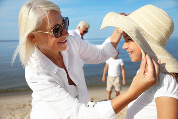 Cute little girl with grandmother spending time together on sea beach