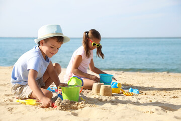 Cute little children playing with plastic toys on sandy beach - Powered by Adobe