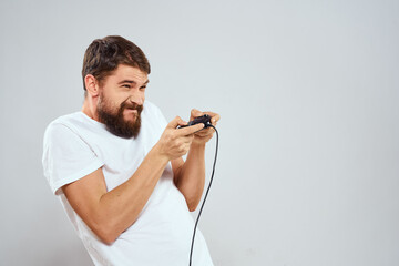 A man with a gamepad in his hands playing games leisure lifestyle technology white t-shirt light background