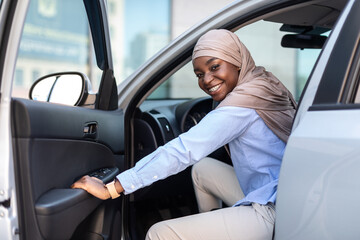 New Car. Happy black muslim businesswoman getting in luxury auto and smiling
