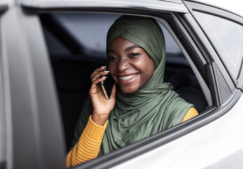 Riding Taxi. Smiling Black Muslim Woman Talking On Cellphone On Car's Backseat